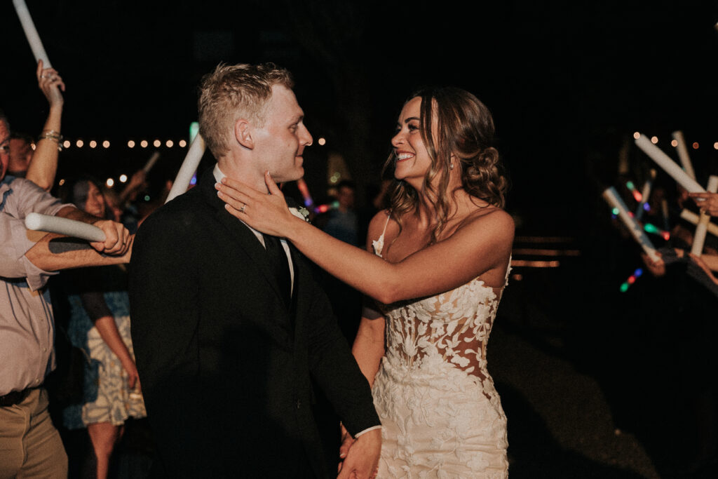 Bride and groom sharing a sweet moment during a glow stick exit, showcasing nighttime wedding send-off ideas that photograph beautifully.